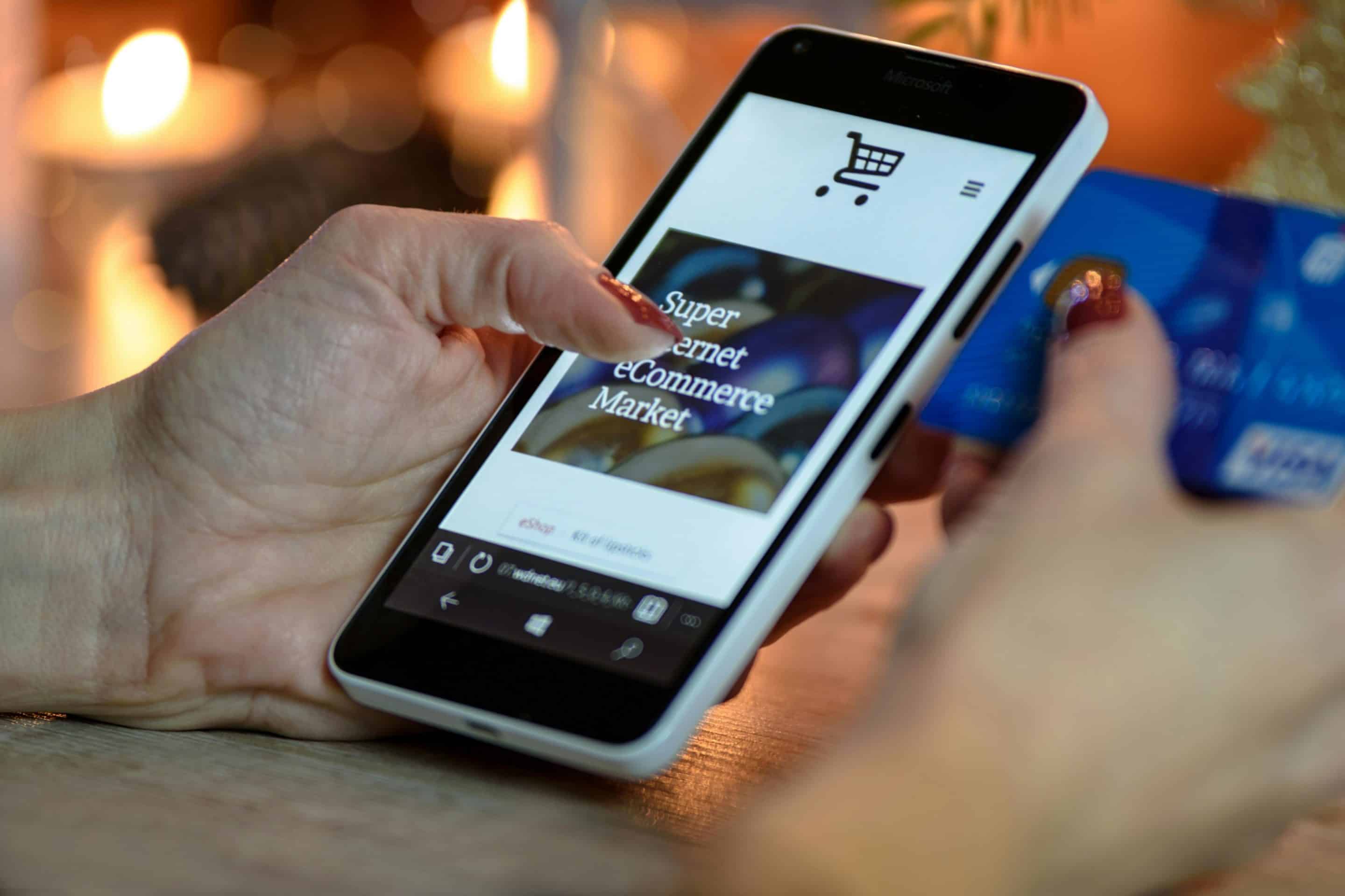 person-using-black-and-white-smartphone-and-holding-blue-card